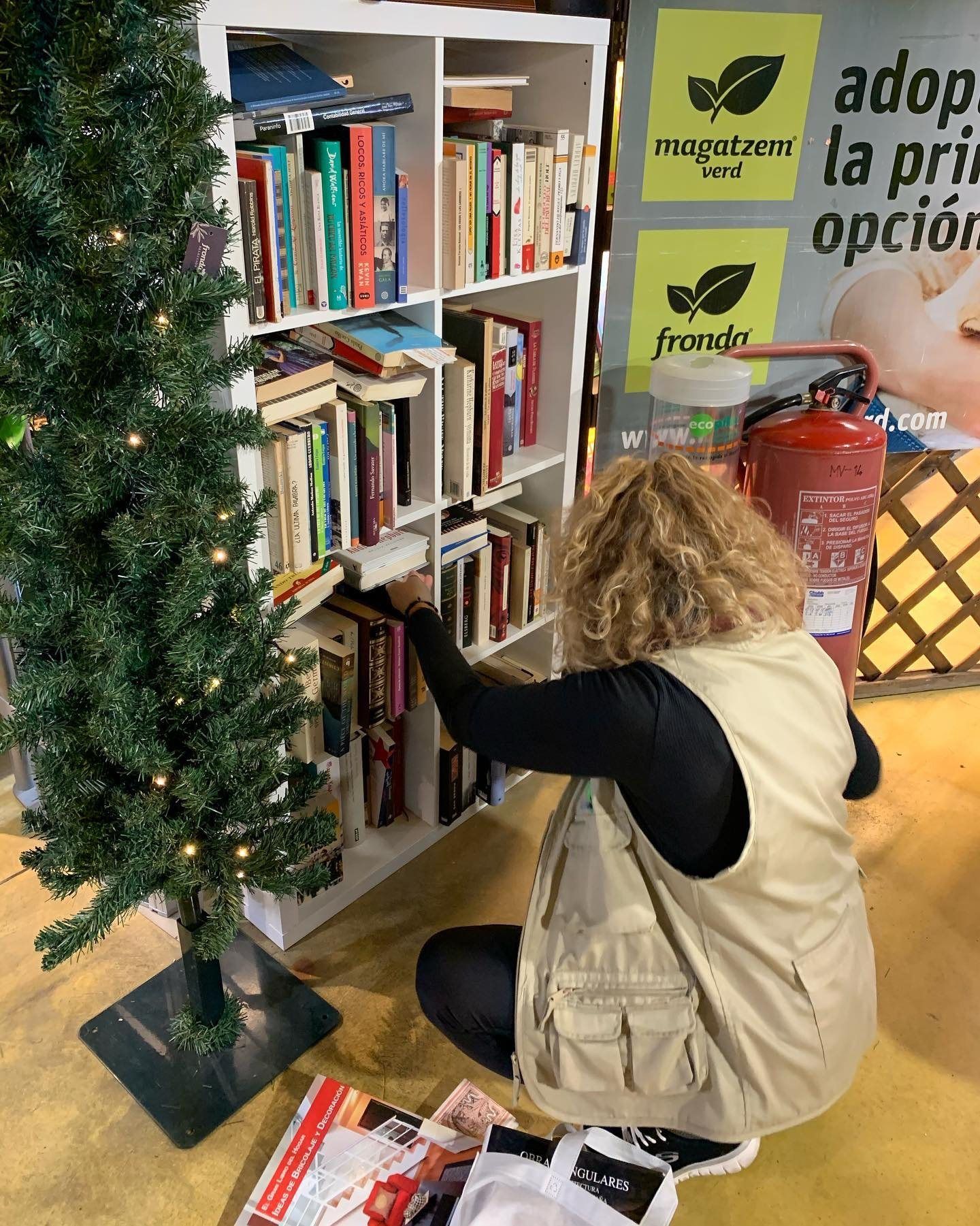 Voluntaria colocando libros en la hucha solidaria de Fronda